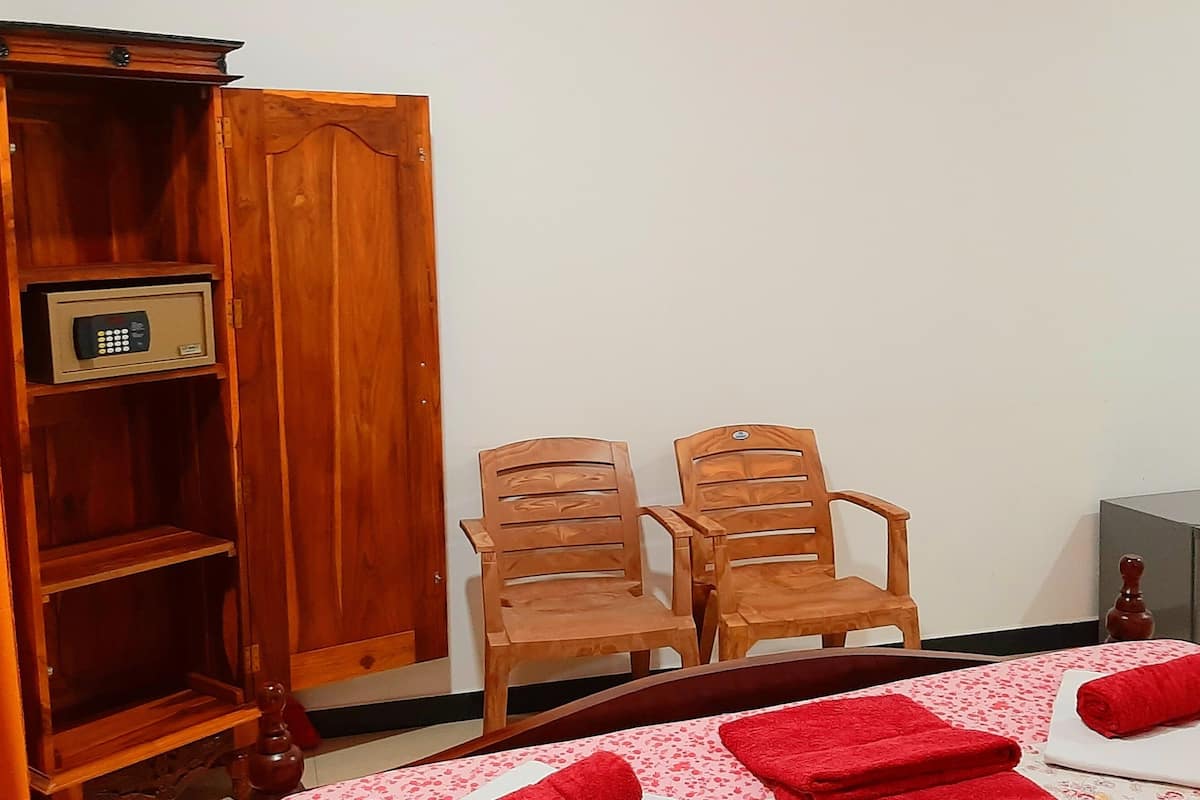 A room with a bed, two wooden chairs, a small cabinet, and a wardrobe.