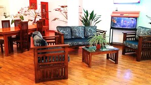 Un salon avec un plancher en bois, un canapé, des fauteuils, une table basse et un téléviseur.