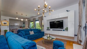 Una sala de estar moderna con un sofá azul, una mesa de centro y un televisor montado en la pared.