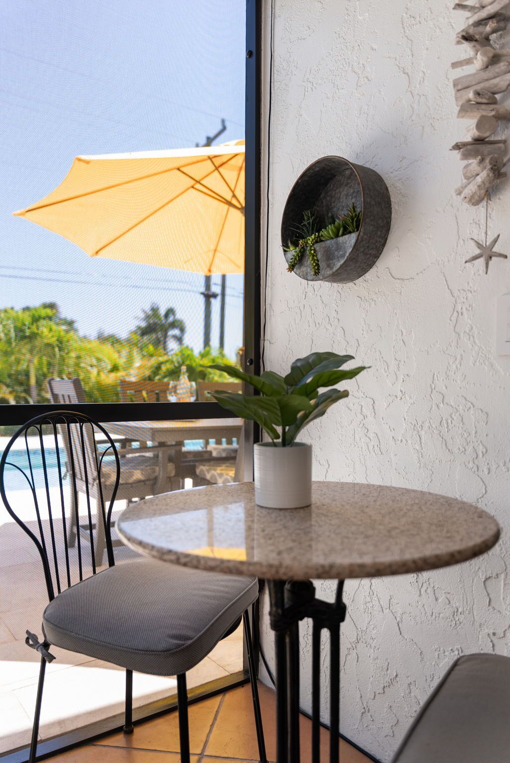 A round table with a potted plant, a chair, and a wall-mounted planter with greenery.