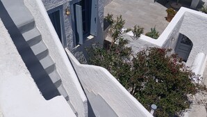 A modern building with a white exterior, a staircase leading to an upper level, and a small outdoor seating area with a table and chairs. - Authentic Castle House in Santorini(sleeps 5) (Pyrgos Kallistis)