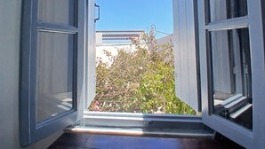 An open doorway leading to a balcony with a view of a building and foliage. - Authentic Castle House in Santorini(sleeps 5) (Pyrgos Kallistis)
