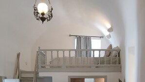 A bedroom with a bunk bed, a chandelier, and a window with curtains. - Authentic Castle House in Santorini(sleeps 5) (Pyrgos Kallistis)