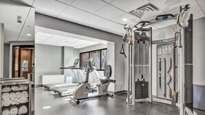 A gym with cardio machines, weightlifting equipment, and a wall-mounted control panel. - King Studio Suite with Kitchenette in the heart of Racine! (Mount Pleasant)