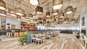 A spacious restaurant with high ceilings, wicker pendant lighting, and a central bar area. - King Studio Suite with Kitchenette in the heart of Racine! (Mount Pleasant)