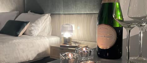 A neatly arranged bedroom with a bed, bedside table, and a bottle of champagne.