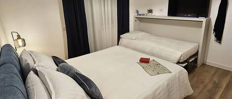 Habitación de hotel con una cama grande, un sofá, un televisor de pantalla plana y una lámpara en el techo.