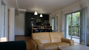 Ein modernes Wohnzimmer mit einer Ledersofa, einem Holztisch und einer Küche im Hintergrund.