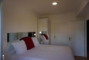 A bedroom with a bed, a wardrobe, and a mirror.