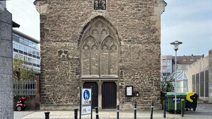 Un edificio histórico de piedra con una amplia entrada en arco y una ventana en arco más pequeña arriba.