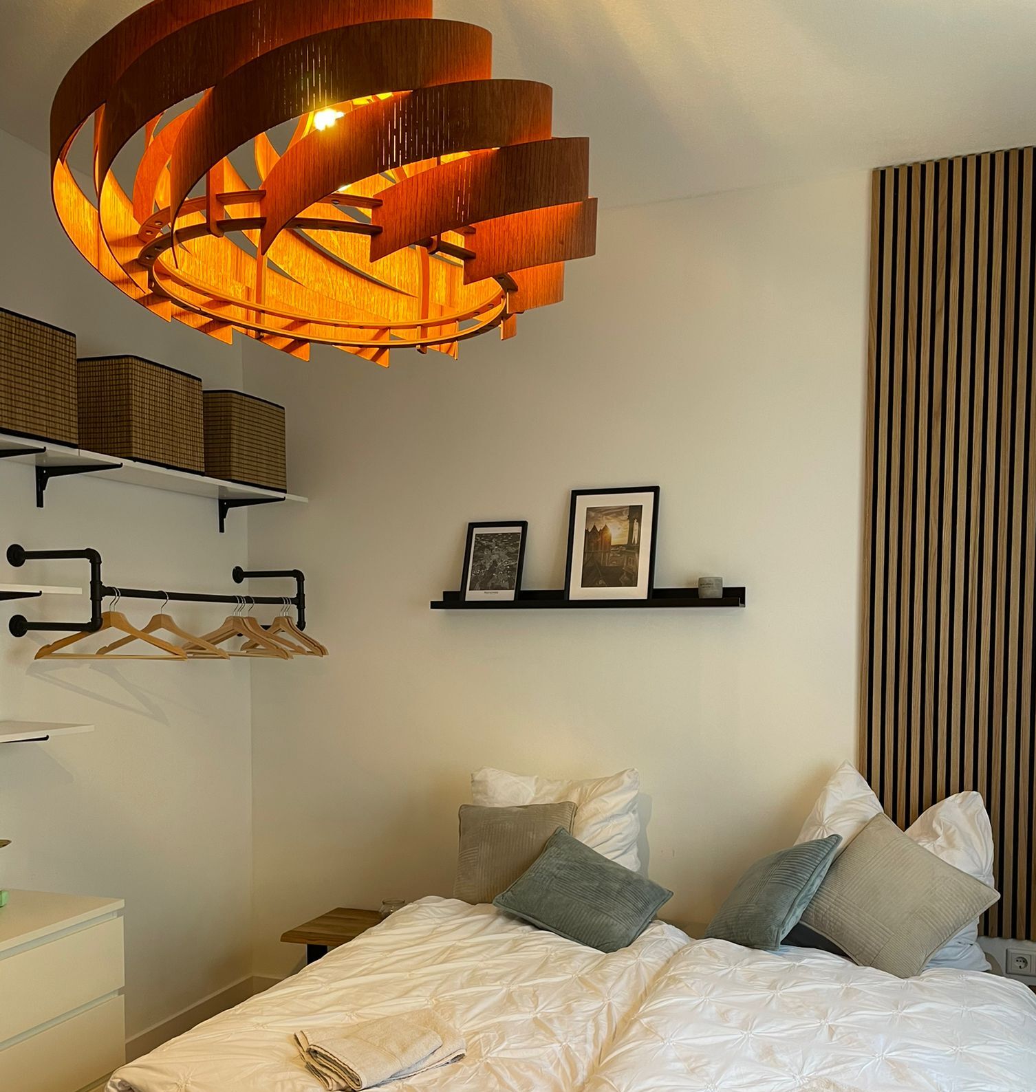 A modern bedroom with a large bed, a unique circular light fixture, and a striped curtain.