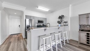 Une cuisine moderne dotée d’un îlot central, de tabourets de bar et d’un porte-ustensiles suspendu.