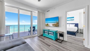 Une chambre d’hôtel moderne dotée d’un balcon, d’une grande fenêtre, d’un lit, d’un bureau et d’un meuble de rangement de couleur turquoise.