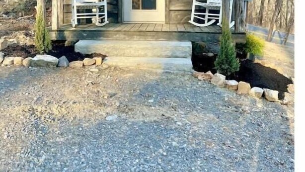 A small cabin with a porch, two rocking chairs, and a door. - Fishing Cabin Getaway (Grant)