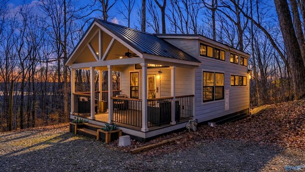 A two-story cabin with a porch, large windows, and a metal roof, surrounded by trees. - Waterfront Boat Ramp Getaway (Grant)