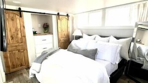 A bedroom with a bed, bedside table, lamp, and a wooden wardrobe. - Waterfront Boat Ramp Getaway (Grant)