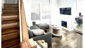 A modern interior with a wooden staircase, a grey sofa, a round coffee table, and a ceiling fan. - Waterfront Boat Ramp Getaway (Grant)