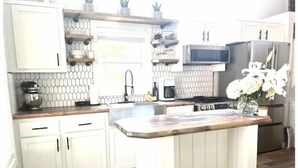 A kitchen with white cabinets, a wooden countertop, a built-in microwave, and a stainless steel refrigerator. - Waterfront Boat Ramp Getaway (Grant)