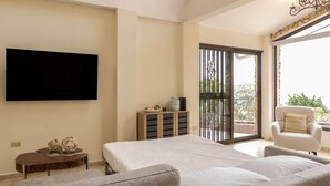 A bedroom with a bed, a TV, a sofa, a chair, a small table, and a balcony with a view. - House in Boquete, House in Boquete with king beds and hot tub (565749) (Alto Jaramillo)