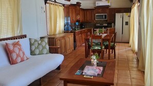 A cozy living room with a sofa, a coffee table, and a dining area with a table and chairs. - Paradise Beach Belize Suite B (downstairs) (Hopkins)