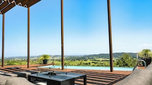 Eine Dachterrasse mit Pool, Gartenmöbeln und Blick ins Grüne.