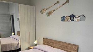 Un letto rifatto con una coperta color lavanda chiaro, due lampade da comodino e un comodino in legno.