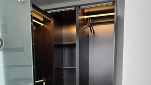 Un armadio moderno con ripiani multipli e spazio per appendere, dotato di una striscia illuminante.