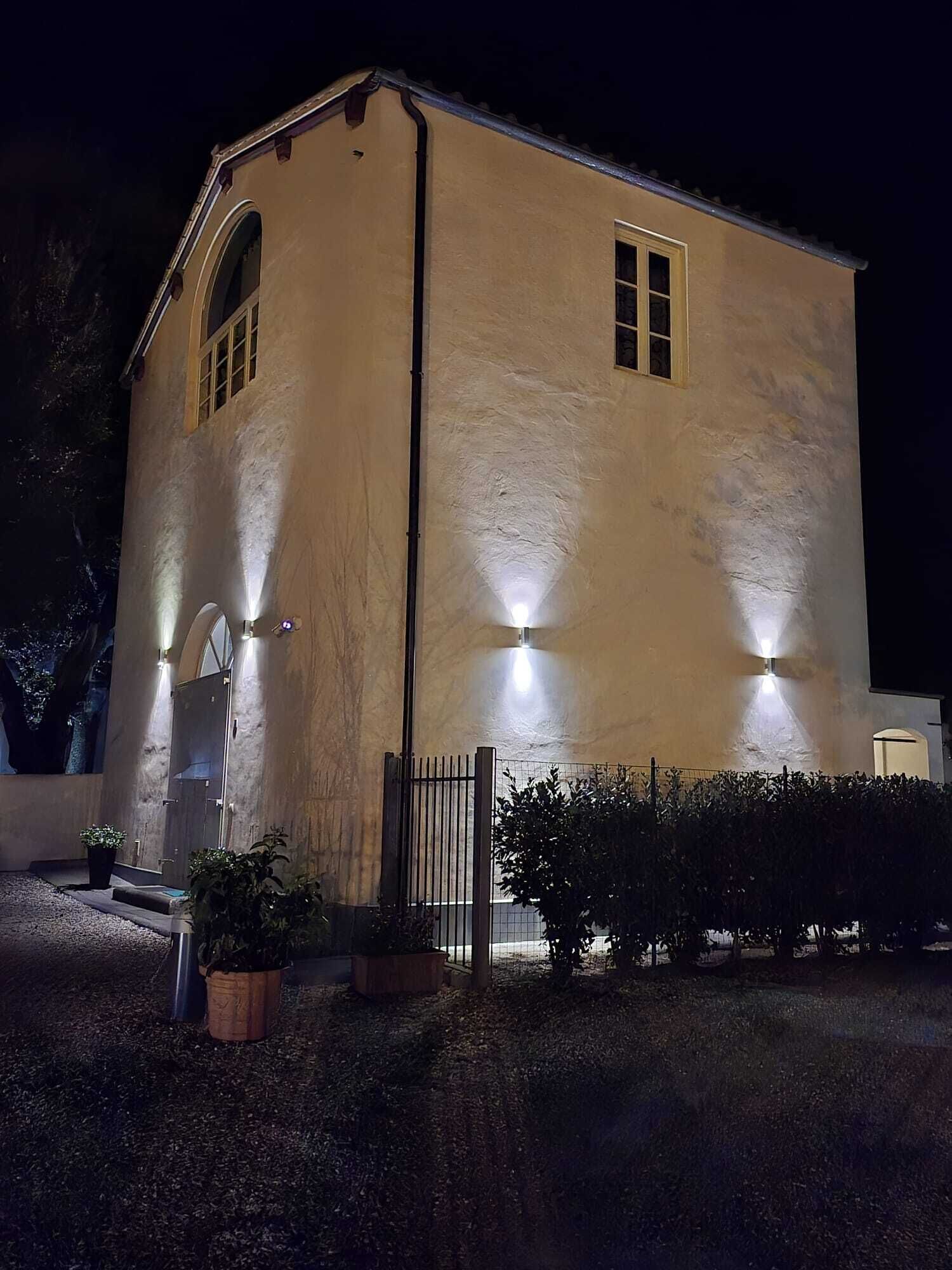 Un edificio con facciata beige, un unico ingresso ad arco e un vialetto recintato.