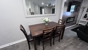 A dining area with a wooden table and chairs, a vase with white flowers, and a large mirror on the wall. - A Home Stay on Business Trip - Near Airport (Atlanta)