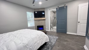 A bedroom with a bed, a fireplace, a TV, and a sliding door to a bathroom. - A Home Stay on Business Trip - Near Airport (Atlanta)