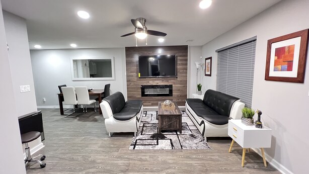 A modern living room with a fireplace, a dining area, and a TV mounted on the wall. - A Home Stay on Business Trip - Near Airport (Atlanta)