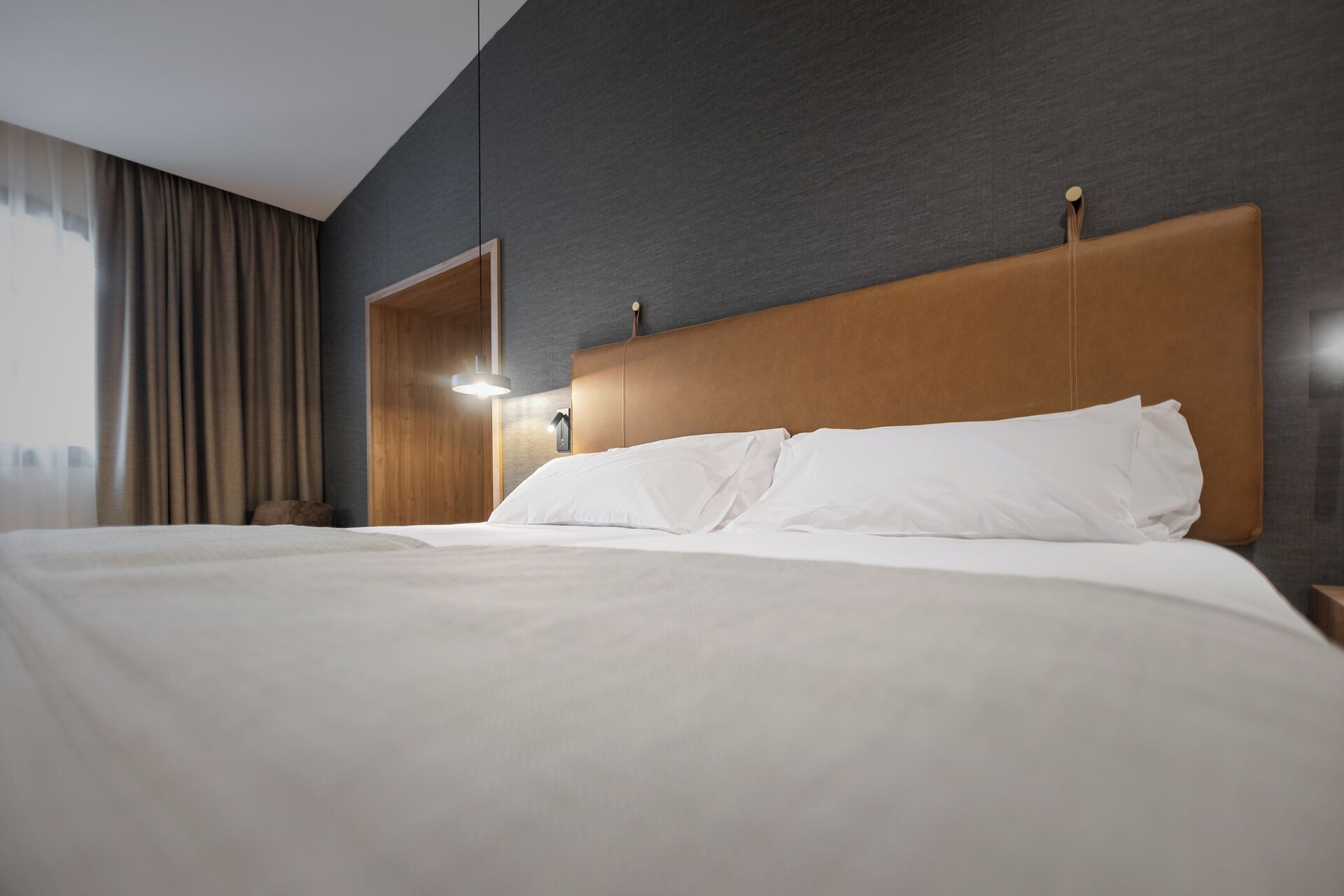 Een hotelkamer met een groot bed, een houten hoofdeinde en een nachtkastje met een lamp.