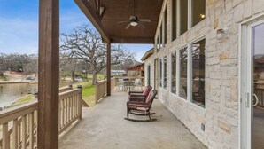 A covered patio with a view of a river, stone walls, and outdoor furniture. - Stunning Lake Home Get Away on The Water! (Gun Barrel City)