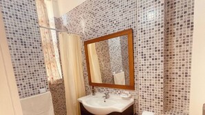 A bathroom with a sink, mirror, toilet, and shower area. - Charming Studio In Casablanca (Casablanca)
