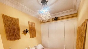 A room with two beds, a wardrobe, a decorative ceiling light, and bamboo wall decor. - Charming Studio In Casablanca (Casablanca)