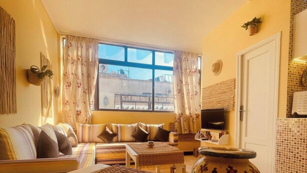 A living room with a sofa, a TV, a patterned rug, and a decorative vase. - Charming Studio In Casablanca (Casablanca)