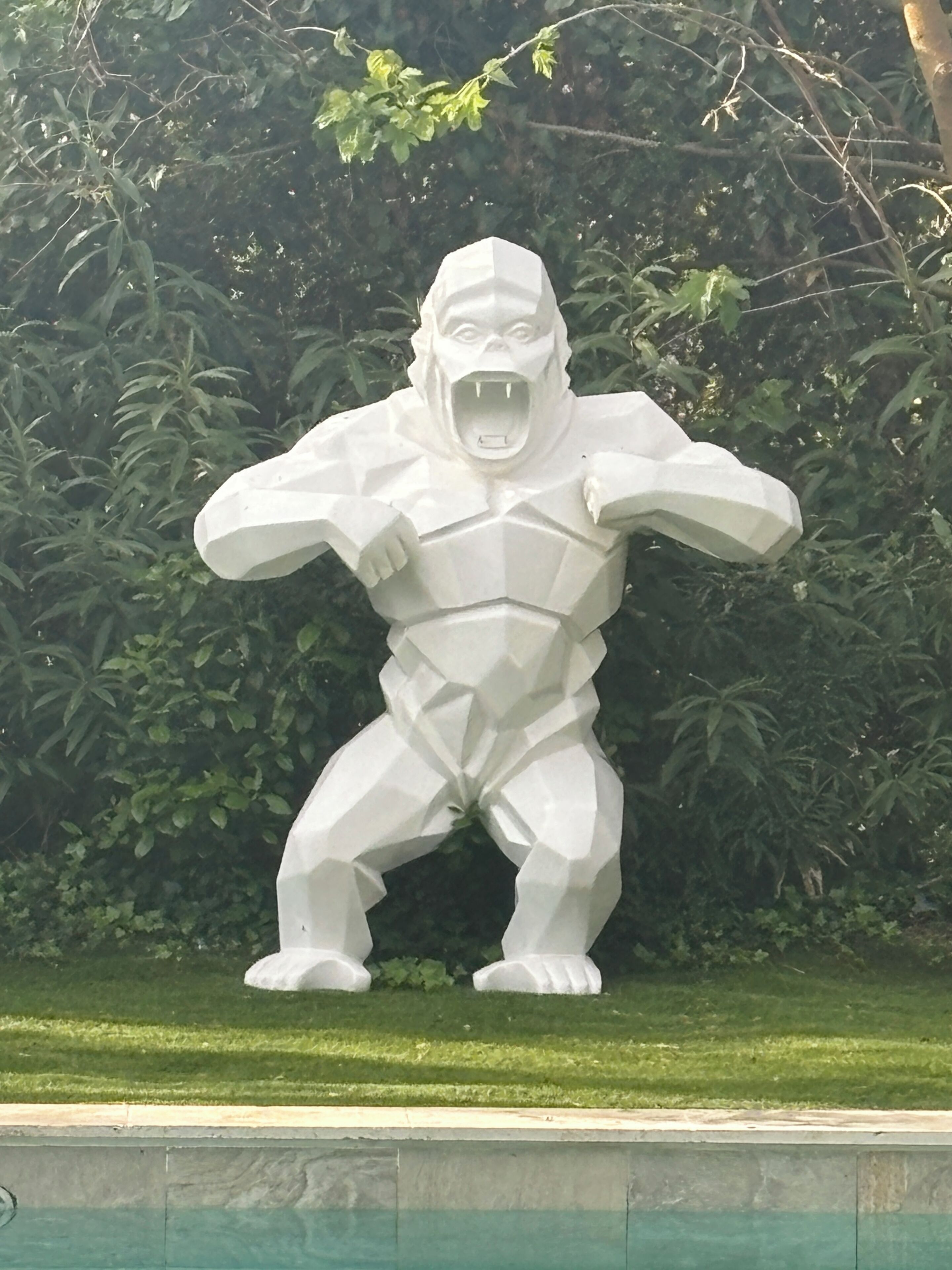 A white statue of a gorilla in a dynamic pose.