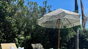 Ein Poolbereich mit Liegestühlen, einem Korbwäscher und einem dekorativen Sonnenschirm.