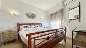 Un dormitorio con cama de madera, mesitas de noche, un espejo y aire acondicionado instalado en la pared.