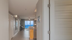 A spacious hallway with a kitchen area, a dining set, and a view of the ocean.