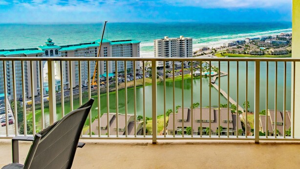 A balcony with a view of a coastal area, including buildings and a body of water.