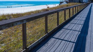 A wooden boardwalk leading to a beach with a building labeled "Whale's Tail Restaurant" in the background.