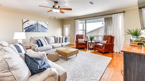 Ein geräumiges Wohnzimmer mit einer Couch, Sesseln, einem Couchtisch und einem Deckenventilator.