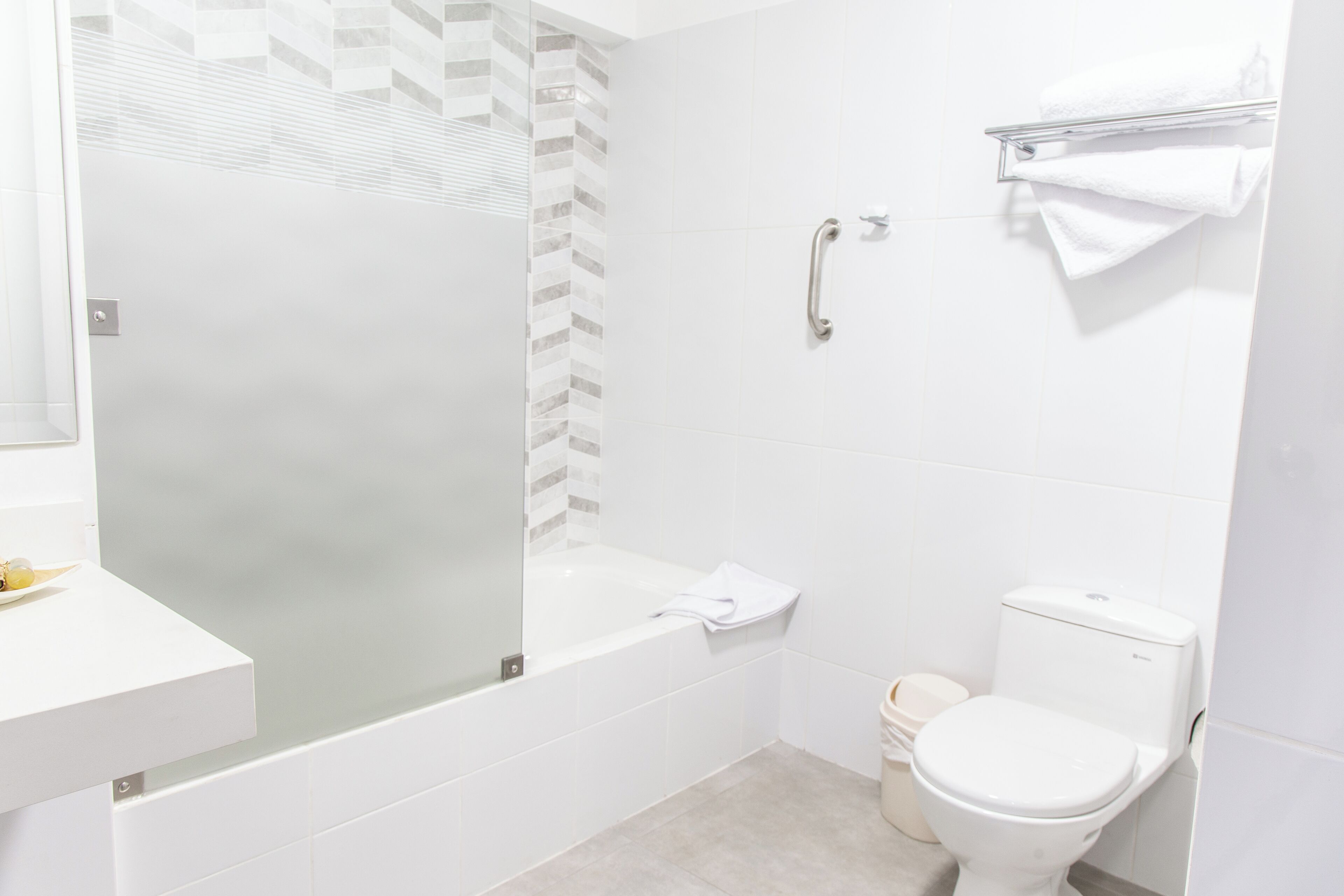 Un baño moderno con ducha envuelta en vidrio, una bañera blanca y un inodoro.