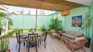 A spacious patio with a round wooden table and chairs, a sofa, and several potted plants. - Hotel San Blas (Lima)