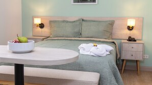 A neatly arranged hotel room with a bed, bedside tables, a round table, and a bench. - Hotel San Blas (Lima)