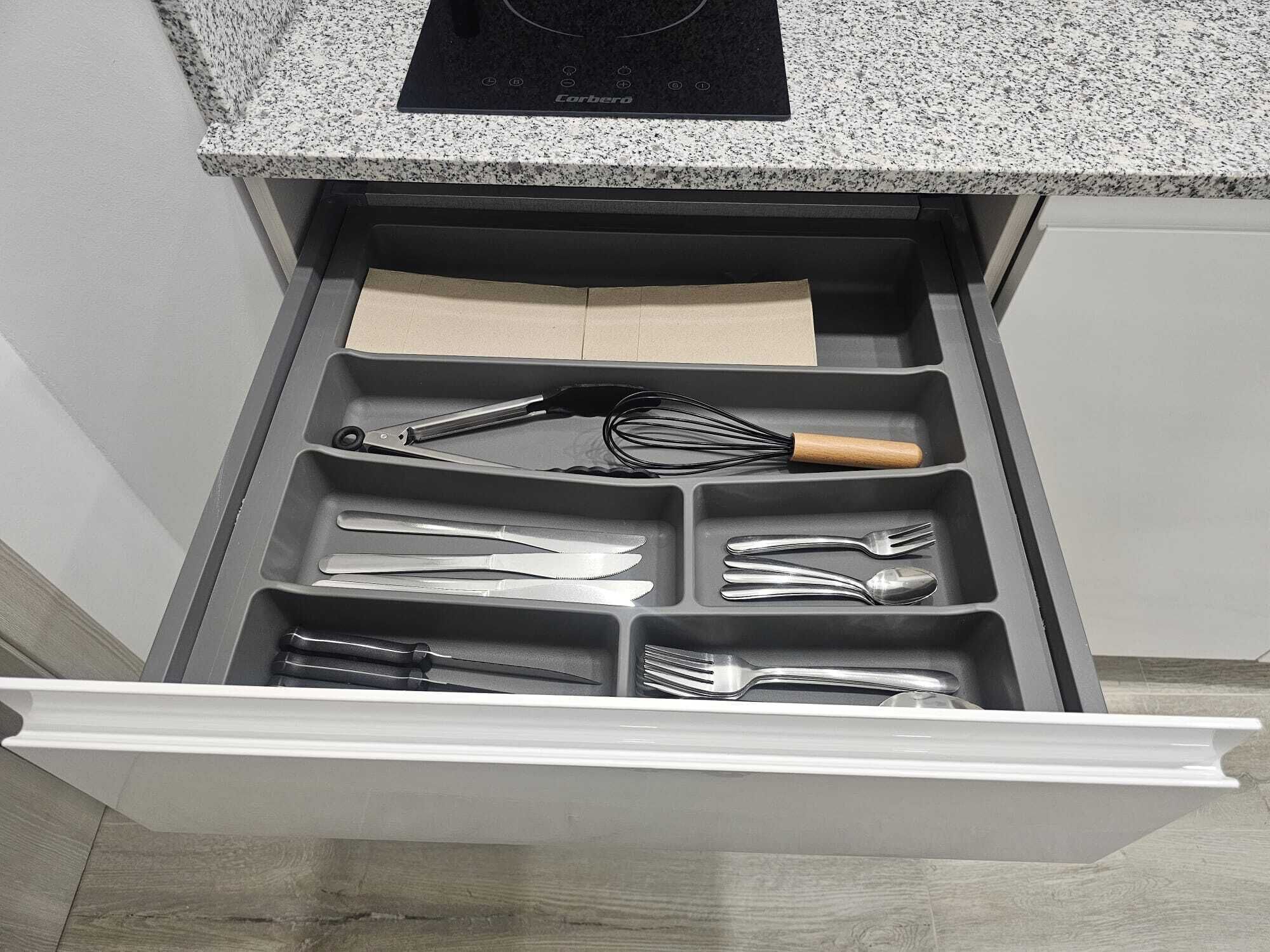 A kitchen drawer with utensils and a cutting board.