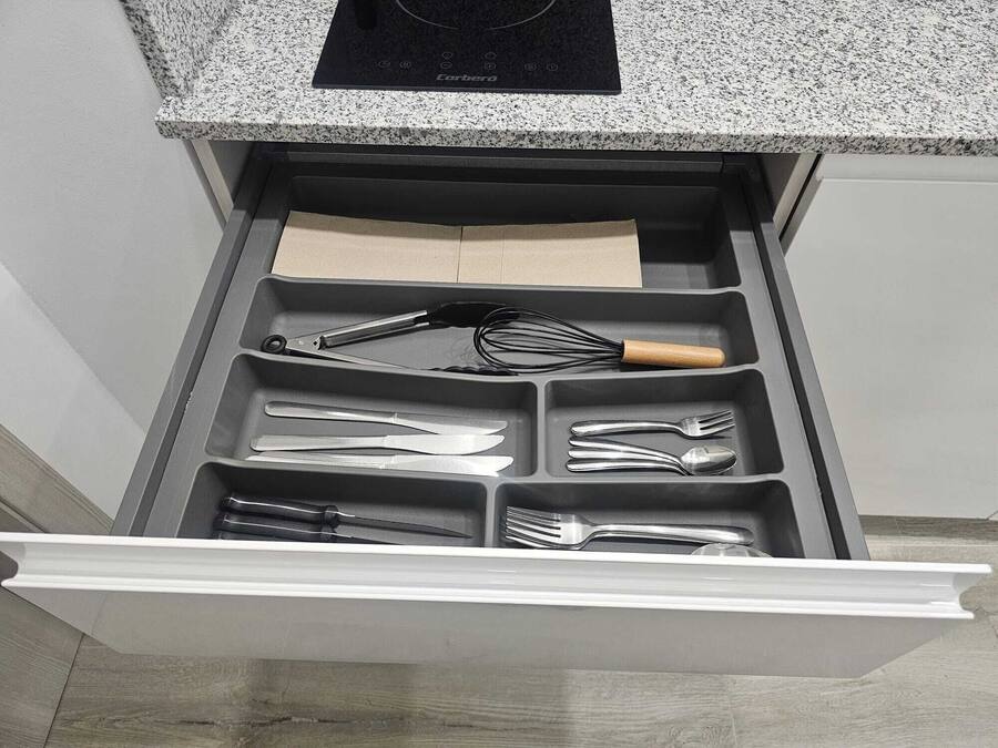 Un cajón de cocina con utensilios y una tabla de cortar.