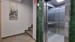 An elevator with a metallic interior and green marble accents. - Apartamentos Antequera (Antequera)