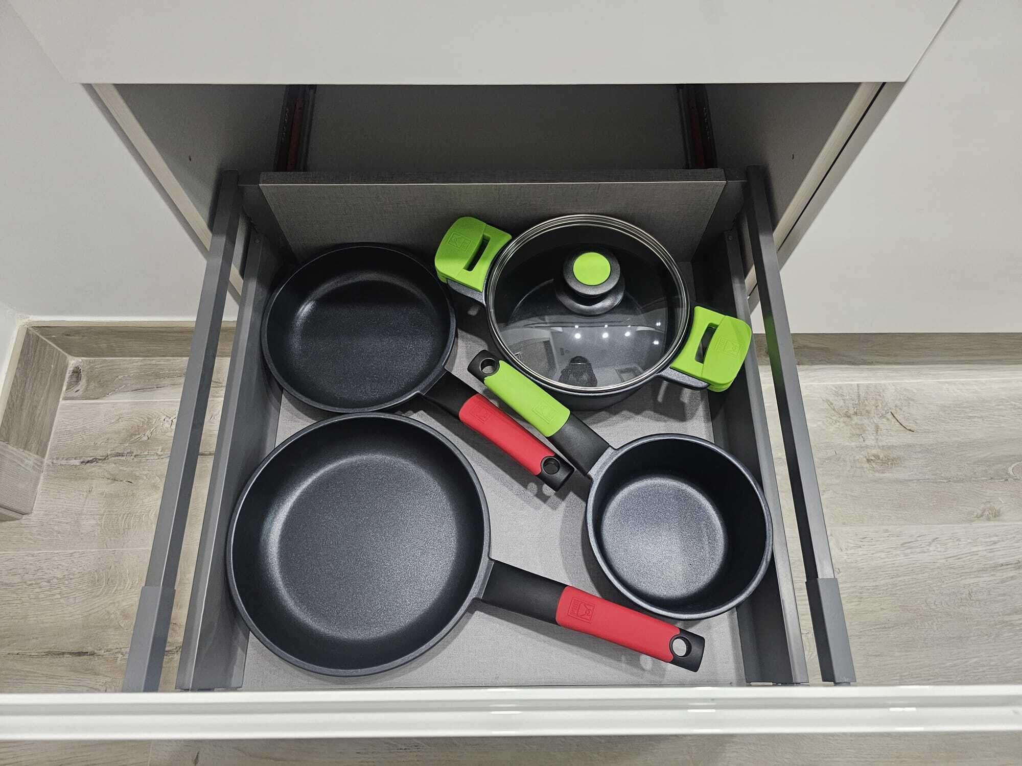 Un cajón de cocina con cuatro sartenes y una olla.